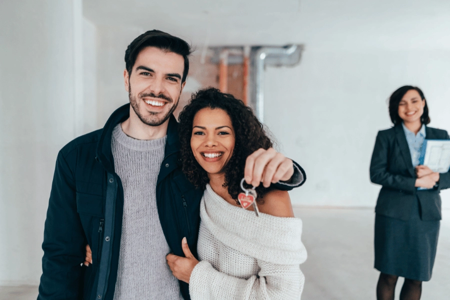 cute couple holding keys to new house after committing to a real estate purchase